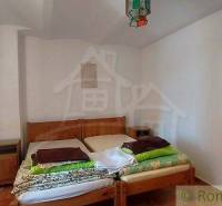 A bedroom with floral curtains, a wooden bed, peculiar property, and an original lamp.