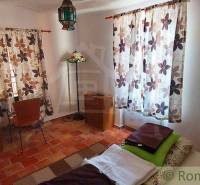 A room with tiled flooring, floral curtains, a lamp, and rustic furniture, suitable for unique properties.