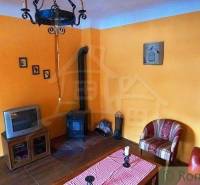 Living room with orange walls, antique furniture, retro television, and rustic decoration.