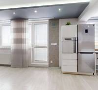 A bright interior of a 4-room apartment with a refrigerator and bar stools.