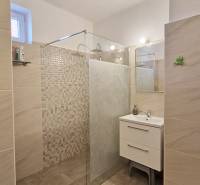 A bathroom in a family house with a shower and a sink on the tiles.