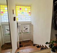 The entrance hall of a family house with a staircase and a stained glass window.