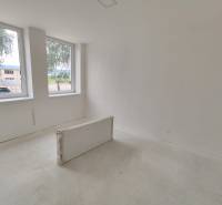Empty room in a 3-bedroom apartment with light walls and two large windows.