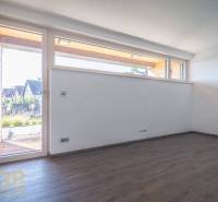 Empty room with a large window, white walls, and wooden floor in a family house.