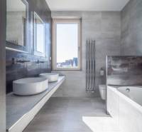 A bathroom in a family house with two sinks, a bathtub, and a large window.