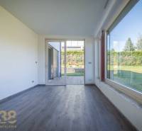 Interior of a family house with wooden flooring and a view of the garden through a large window.