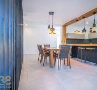 Dining area and bar counter in a family house with wooden furniture and pendant lamps.