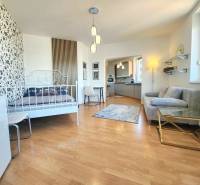 1-bedroom apartment with patterned wallpaper, wooden flooring, kitchen, and seating area.