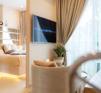 A bright interior of a 2-room apartment with a large TV and curtains by the French window.