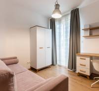 A room in a 3-room apartment with a sofa, wardrobe, desk, and chair.