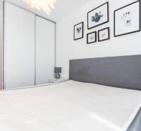 Bedroom in a 3-room apartment with a bed, lamp, and paintings on the wall.