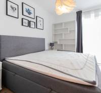 A bedroom in a 3-room apartment with a bed, nightstands, and paintings on the wall.
