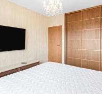A bedroom with a bed, a large wardrobe, a television, and a chandelier in a three-room apartment.