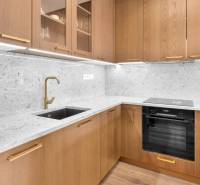 A kitchen in a 3-room apartment with wooden cabinets and a stone countertop.