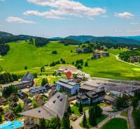 An aerial view of lush green hills and buildings in Donovaly.
