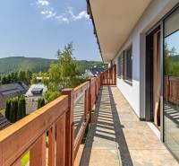 The balcony of a 3-room apartment in Donovaly with a view of the forests and rooftops.