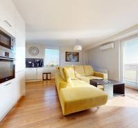 Living room with kitchen in a 3-room apartment with a yellow sofa and white furnishings.