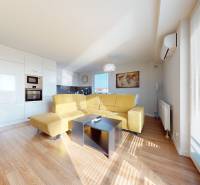 Living room in a three-room apartment with a comfortable sofa and a kitchen unit.