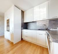 A kitchen in a 3-room apartment with white cabinets and wooden flooring.