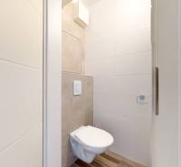 A bathroom in a 3-room apartment with a toilet and tiles on the walls.