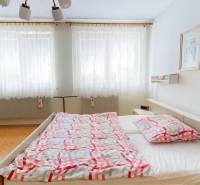 A bedroom in a family house with a double bed, curtains, and paintings on the wall.