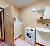 A bathroom in a family house with a washing machine, a bathtub, and a sink.