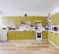 A kitchen in a family house with olive cabinets, appliances, and wooden flooring.