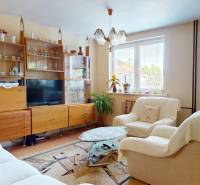 Living room with white furniture and a wooden wall unit in a family house.