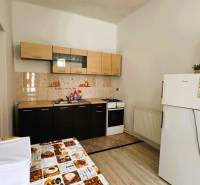 A kitchen with tiles, a kitchen unit, a stove, and a refrigerator in a family house.
