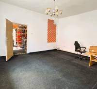 A room in a family house with a carpet, a table, a chair, and an open door.