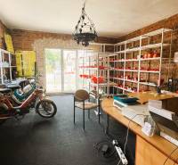 Interior of a family house with brick walls, a motorcycle, and shelves with goods.