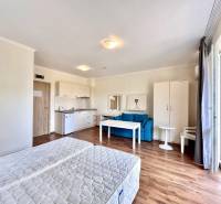Recreational apartment with beds, a kitchenette, a blue sofa, and a table with two chairs.