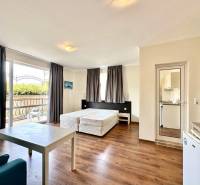Interior of a holiday apartment with beds, a balcony, and a kitchenette, ideal for a vacation.