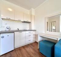 A kitchen area in a holiday apartment with light furniture and a mirror.