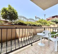 Terrace of a recreational apartment in Nessebar with garden furniture and a view of greenery and a fence.
