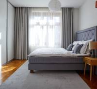 A bright bedroom with a gray bed, a nightstand, and large windows in a 4-room apartment.