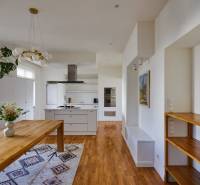 A kitchen in a 4-room apartment with a wooden table, floor, and white cabinets.