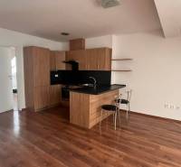The kitchen in a 3-room apartment with wooden floors, a black countertop, and two chairs.