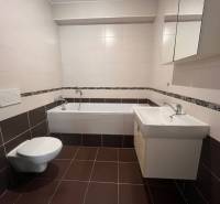 Bathroom in a 3-room apartment with brown and white tiles, a bathtub, a sink, and a toilet.