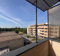 The view from the balcony of a 3-room apartment in Dunajská Streda to the surrounding buildings and greenery.