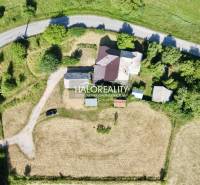 Aerial view of a family house in Ploské surrounded by a grassy plot and a road.