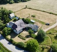 A family house in Ploské, surrounded by trees and agricultural landscape near the main road.