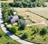 A family house in the village of Ploské surrounded by greenery and an access road.
