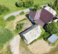 A family house in Ploské surrounded by greenery and an access road by the house.