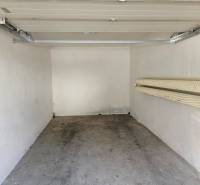 The interior of a garage with an open door and hooks on the wall.