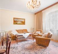 Living room in a family house with a chandelier, sofa, carpet, and curtains.