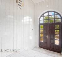 Interior of a family house with entrance doors with glazing, white walls, and tiles.