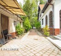 Courtyards of family houses in Žihárec with paving, greenery, and a shed.