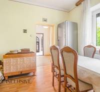 Dining area with a tiled stove and a view of the hallway in a family house.