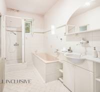 A bathroom in a family house with a bathtub, shower, and sink.